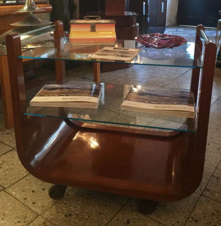 Antique cocktail trolley with glass shelves and polished wood in a classic setting.