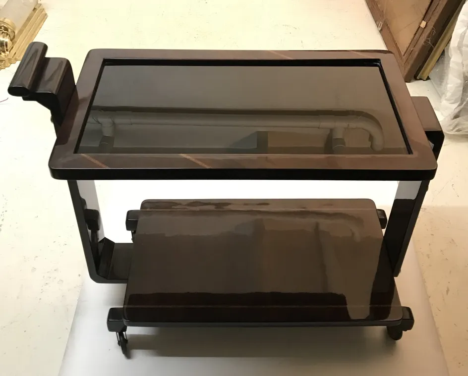Antique cocktail trolley with glass top and wheels.