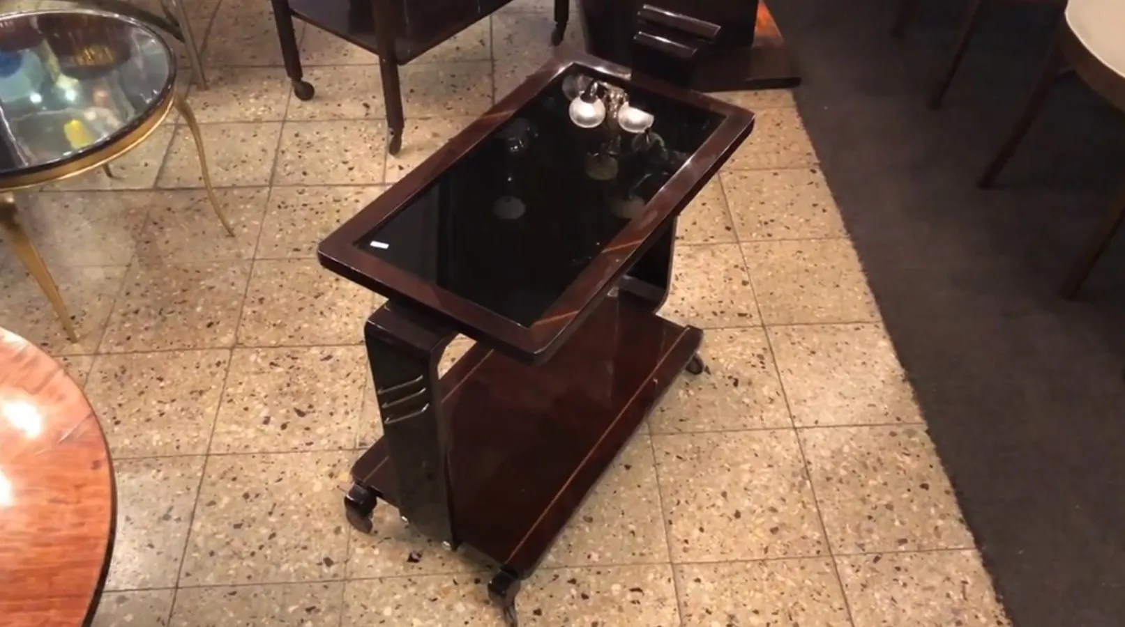 Antique cocktail trolley with black glass in an appealing setting.