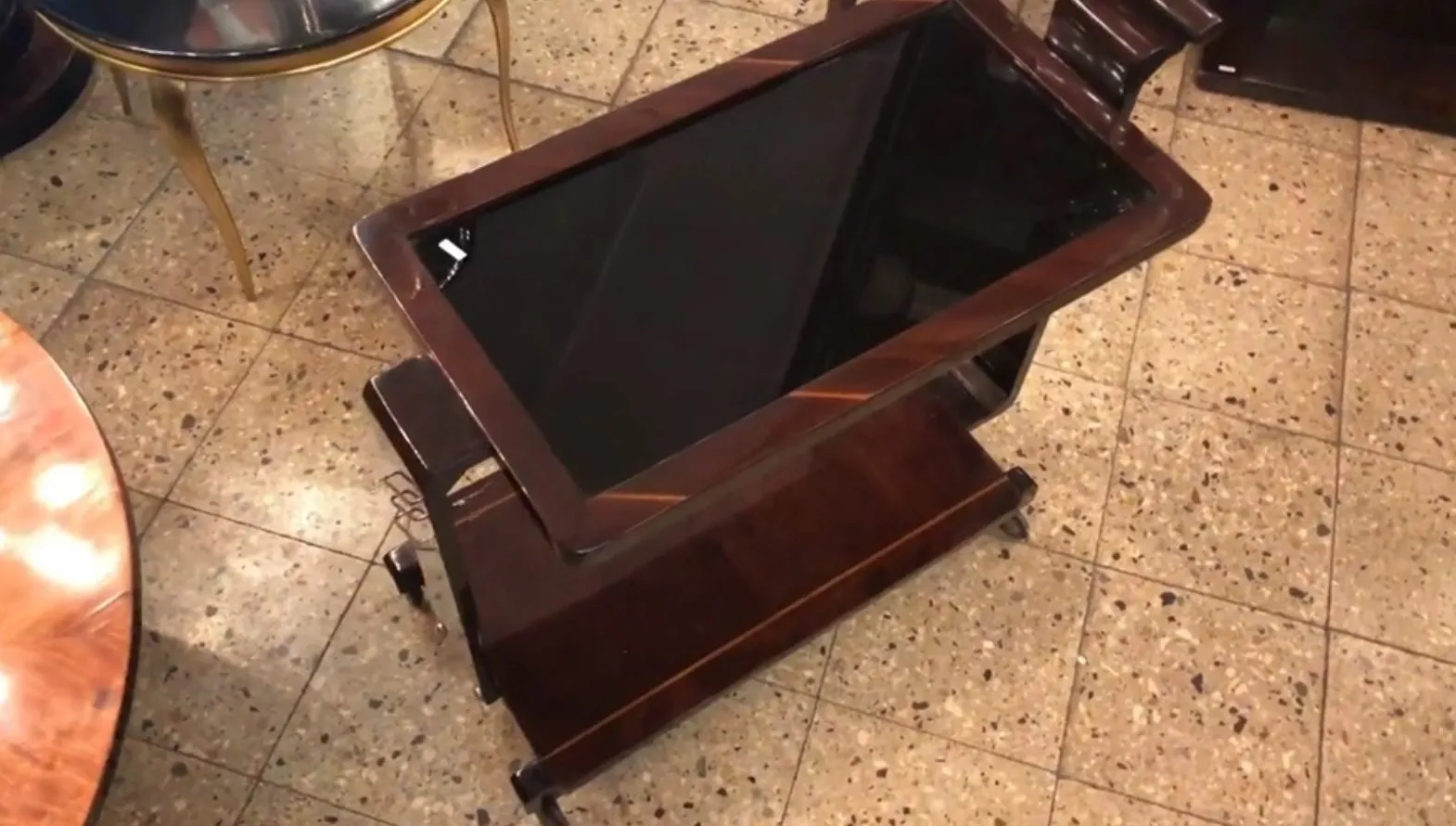 Antique cocktail trolley with glass top in elegant setting.