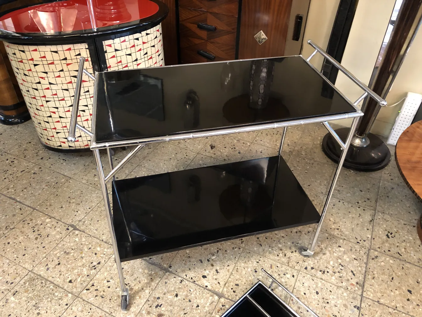 Antique cocktail trolley with two levels and metal frame, black background.