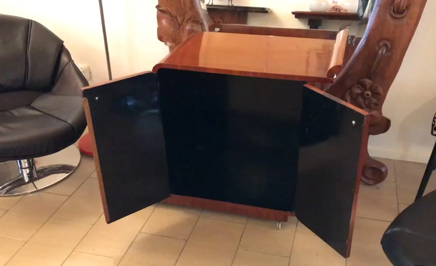 Antique cocktail trolley with wooden finishes and black doors.