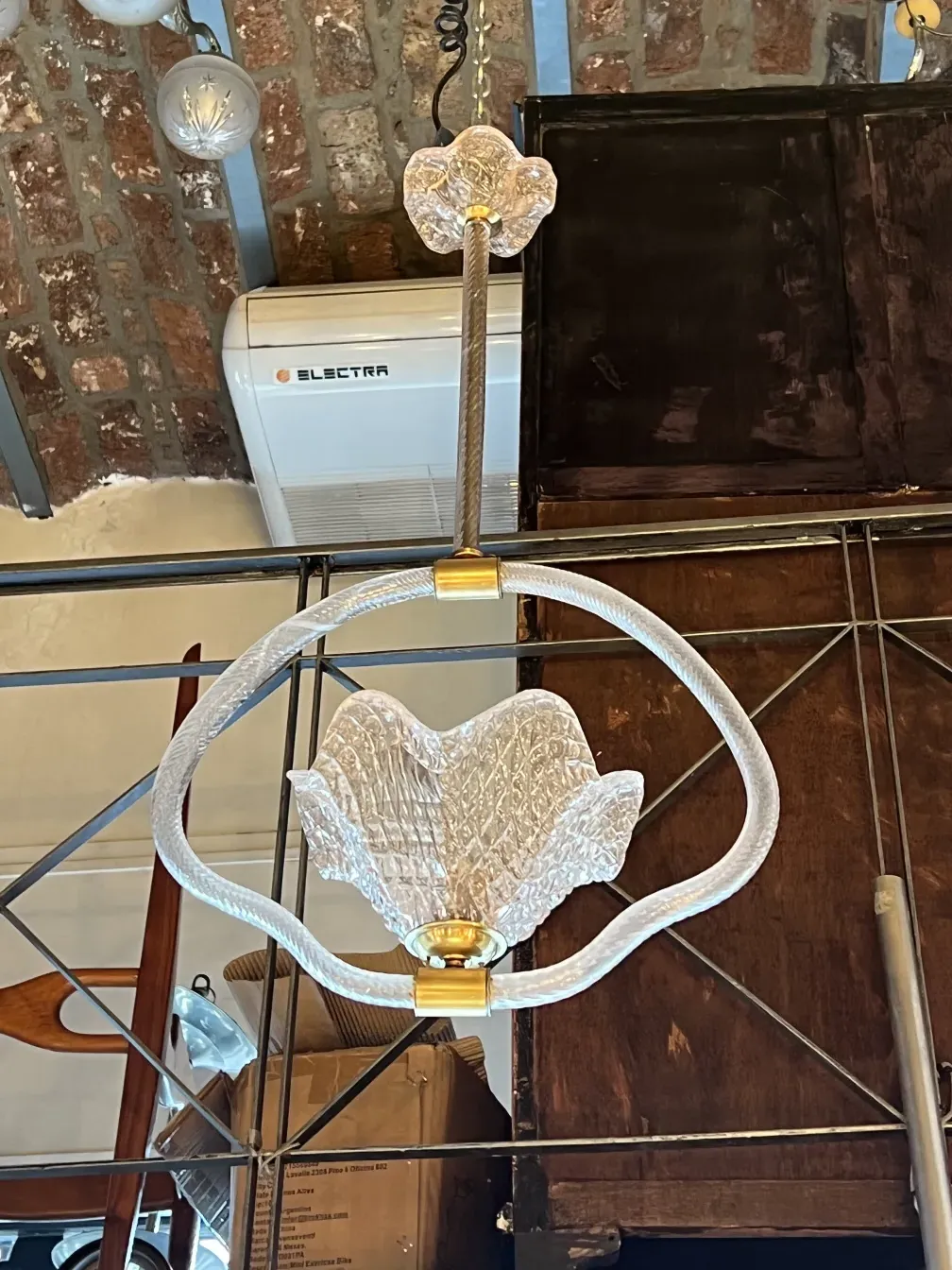 Antique hanging lamp with hexagonal design and golden details against a brick background.