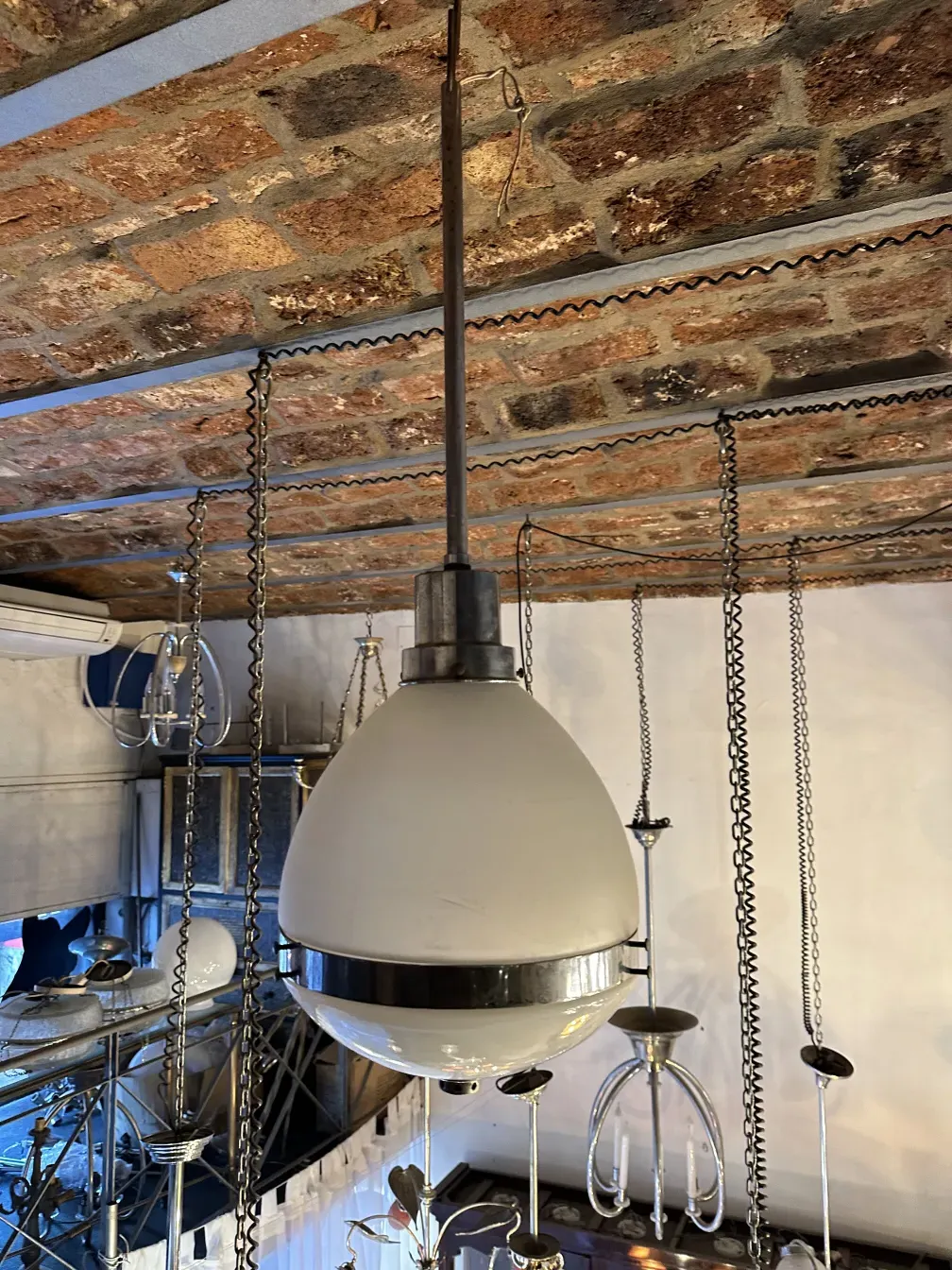 Antique hanging lamp in a contemporary setting, with a metal base and white shade.