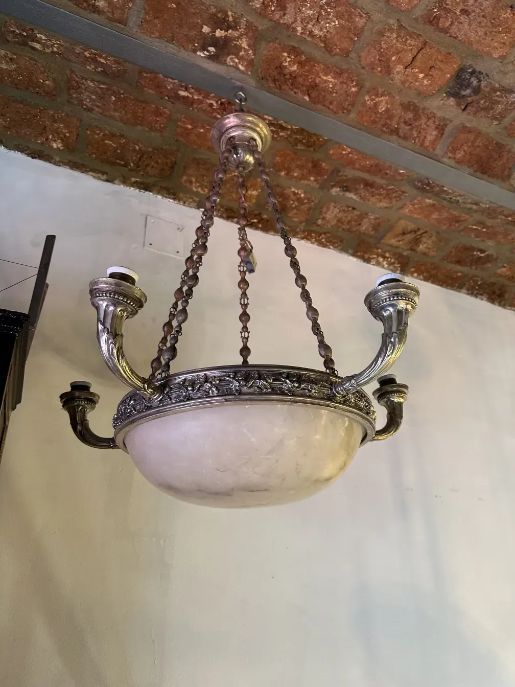 Antique hanging lamp with elegant design, adorned with chains, in a rustic setting.