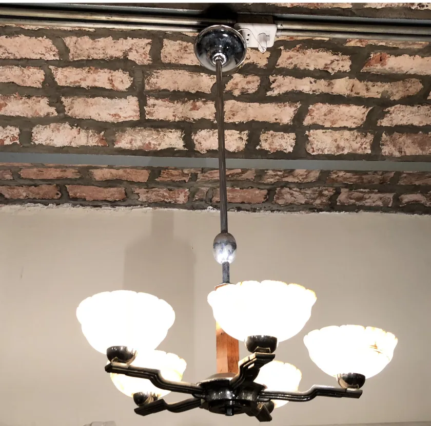 Antique hanging lamp with six white shades in a simple setting.