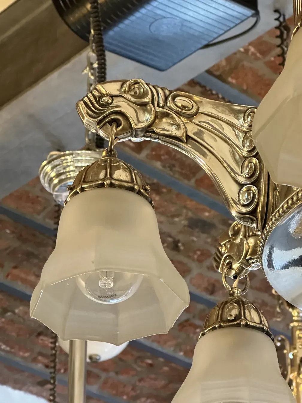 Antique hanging lamp with ornate arms and frosted glass