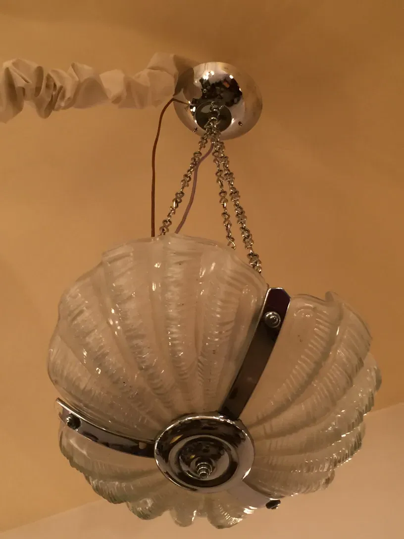 Antique hanging lamp featuring shell-shaped glass with chrome details in a cozy setting.