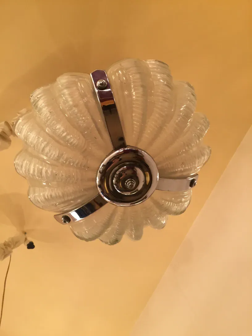 Antique hanging lamp with wavy glass and shiny finish in a warm atmosphere.