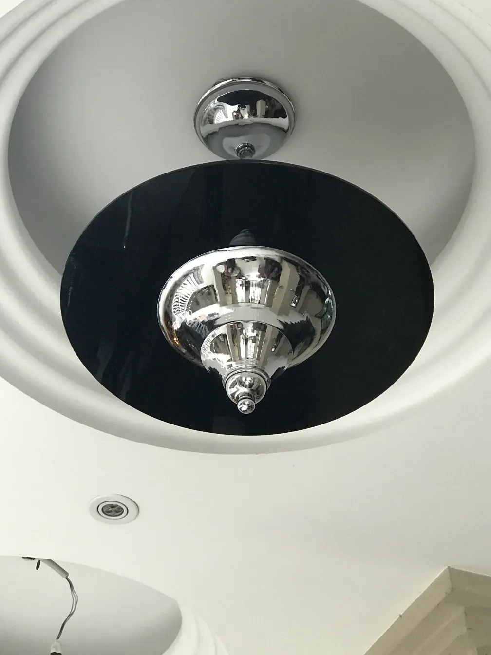 Antique hanging lamp with black and chrome design, set in a modern environment.