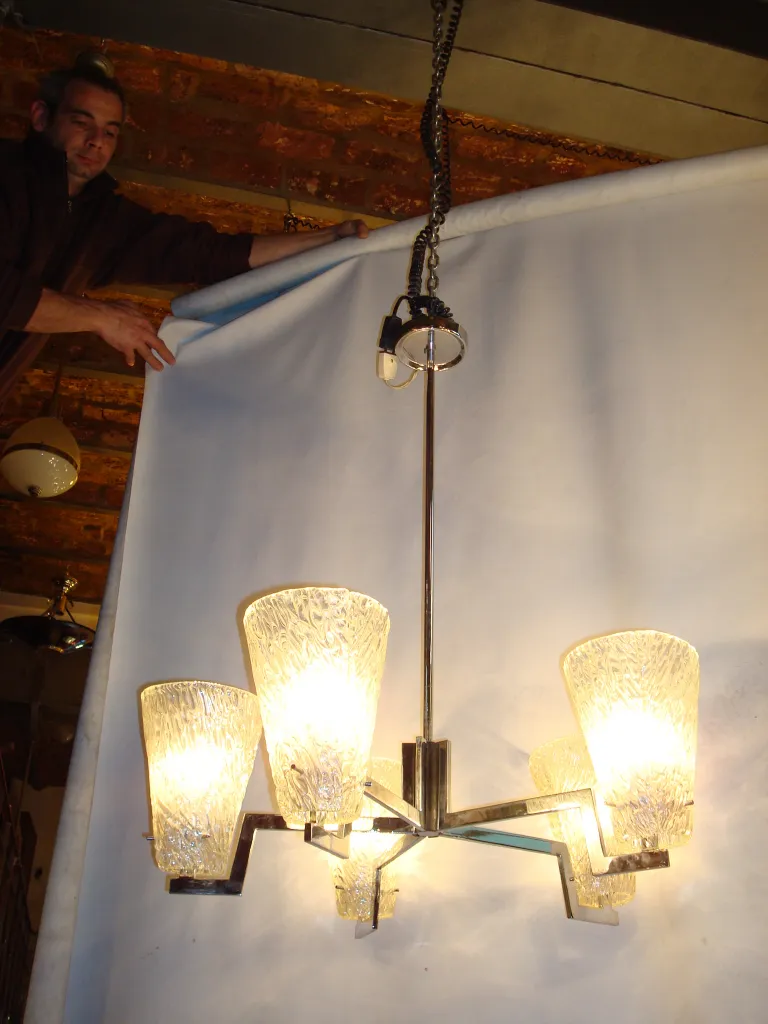 Vintage hanging lamp with multiple lights on, in a bright background.