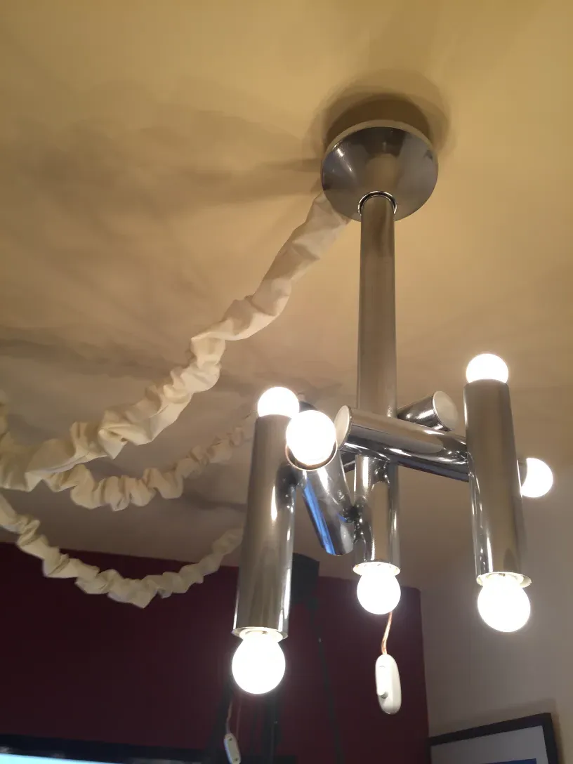 Antique hanging lamp with multiple bright bulbs, in a lit environment.