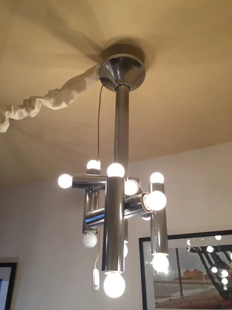 Antique hanging lamp with multiple bright lights in a modern design, set against a light background.