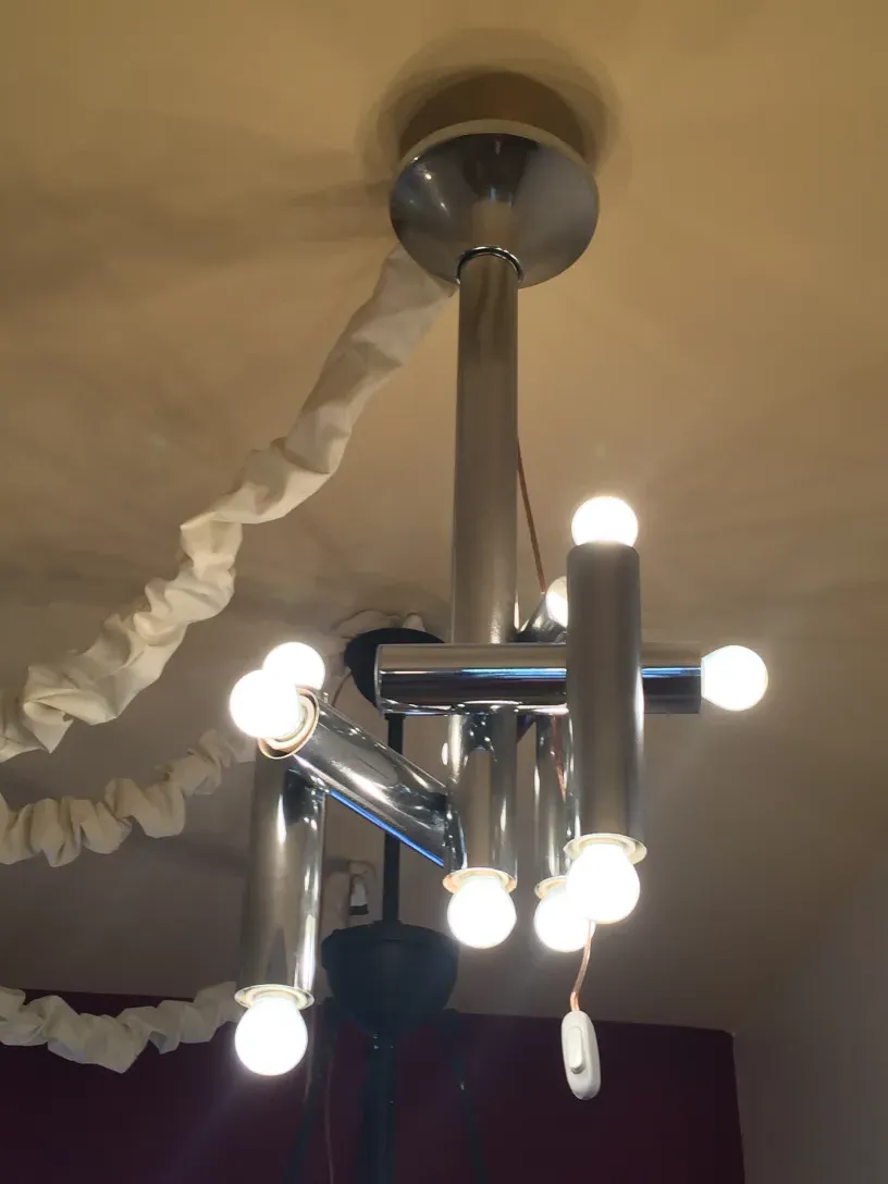 Antique hanging lamp with multiple bulbs against a light wall.
