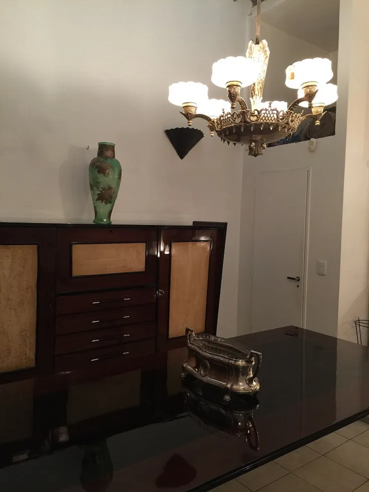 Antique hanging lamp with soft light, in an elegant setting. Next to a green vase.