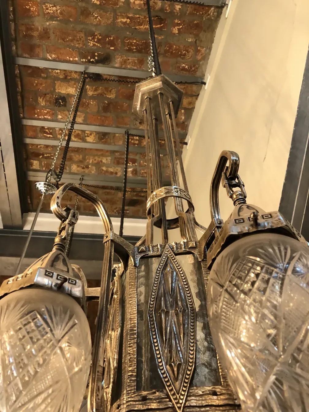 Antique hanging lamp with elegant crystals, suspended in a cozy setting with brick walls.