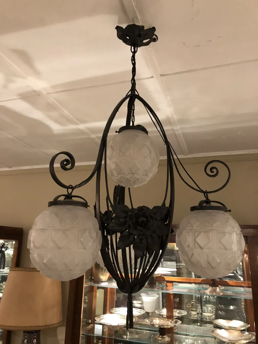 Antique hanging lamp with round bulbs and floral design, set in an elegant environment.