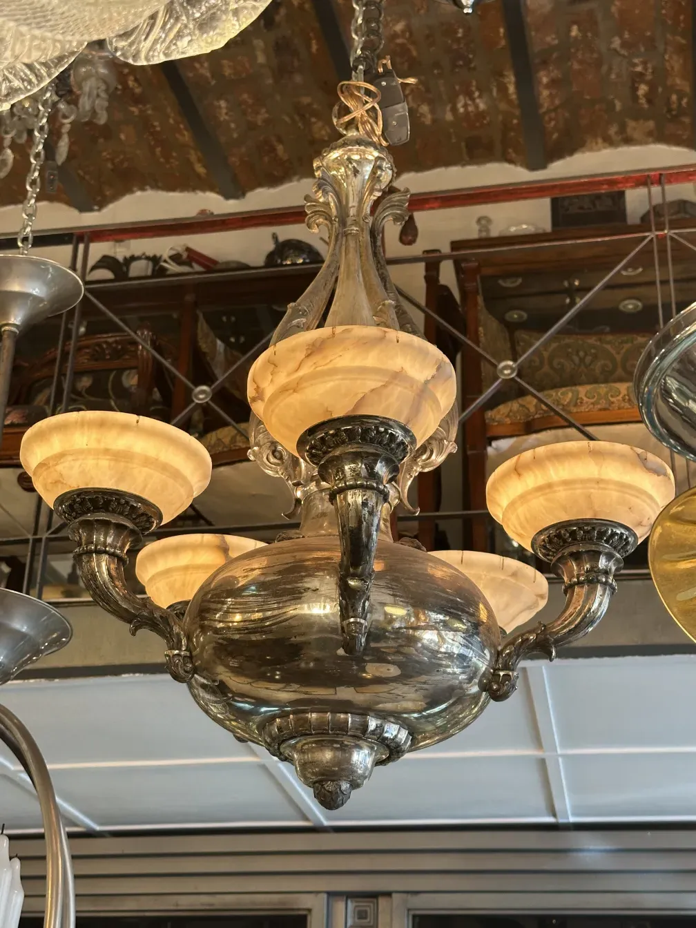 Antique hanging lamp with ornate arms and glowing shades