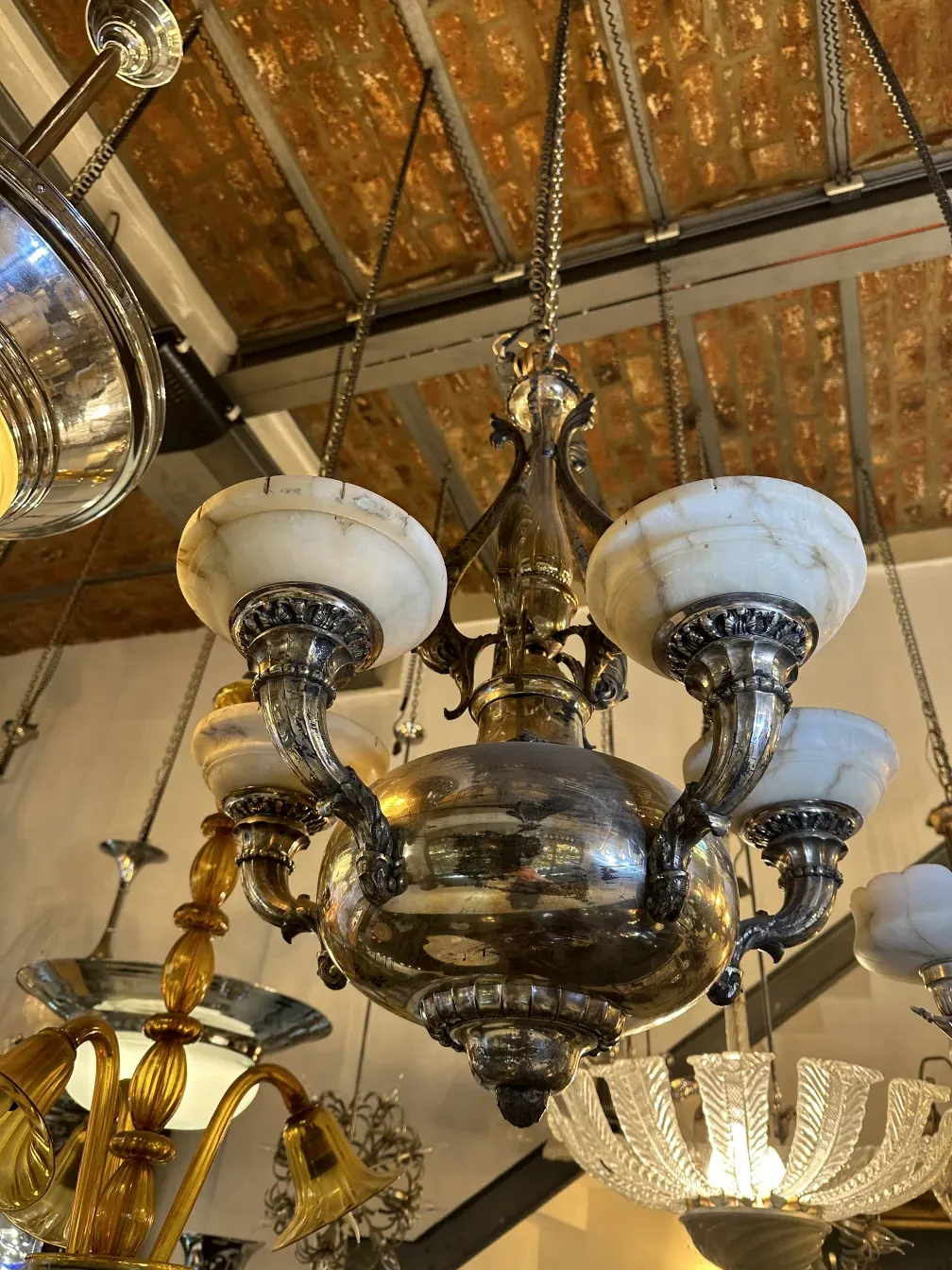 Antique hanging lamp with ornate arms and light tones.