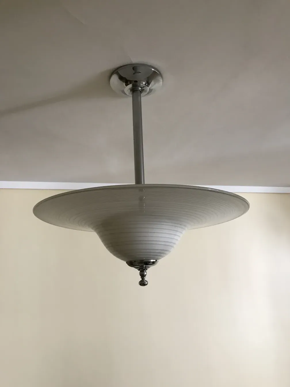 Antique hanging lamp with shiny base in a neutral setting.