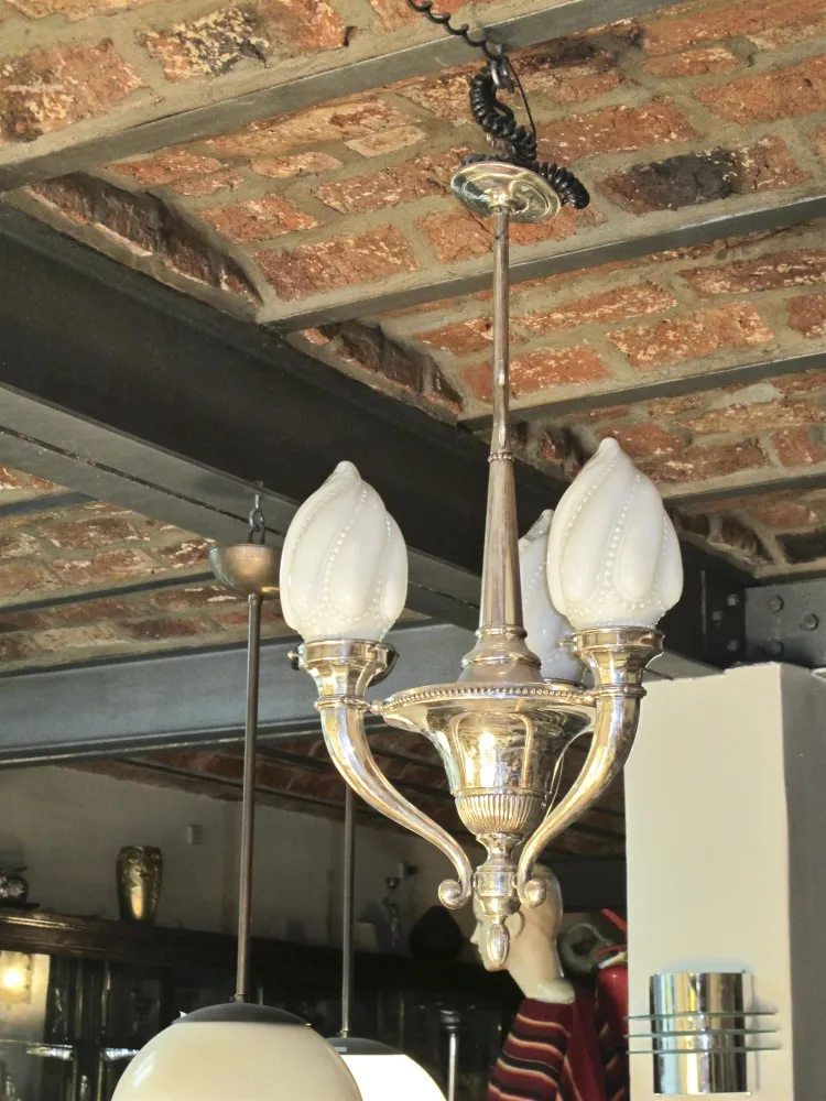 antique hanging lamp with flower-shaped bulbs, suspended from an exposed brick ceiling