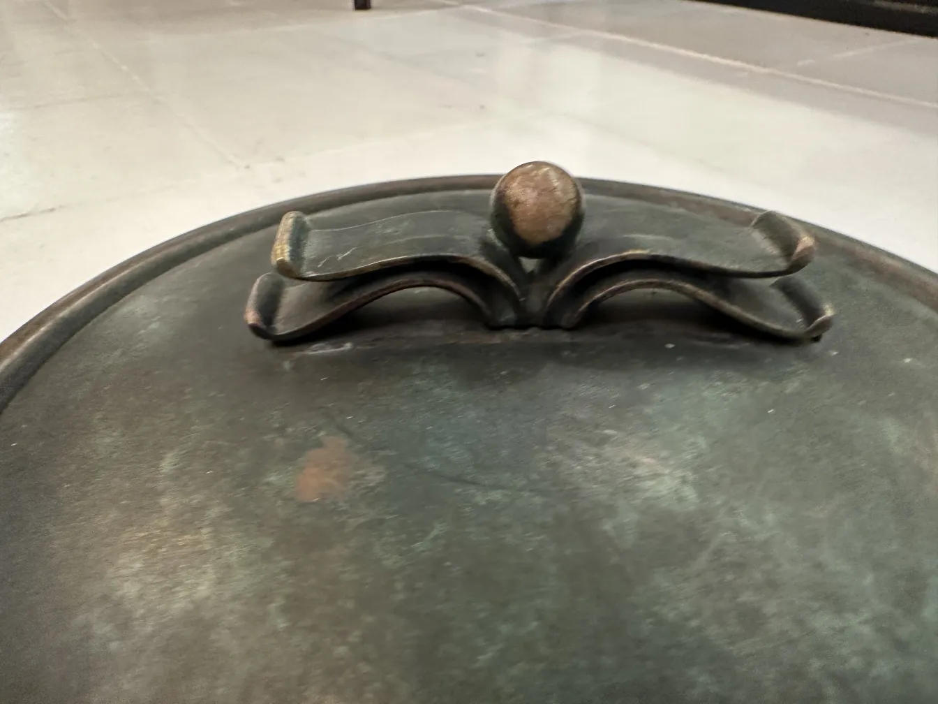 Circular antique box with decorative lid in dark colors.