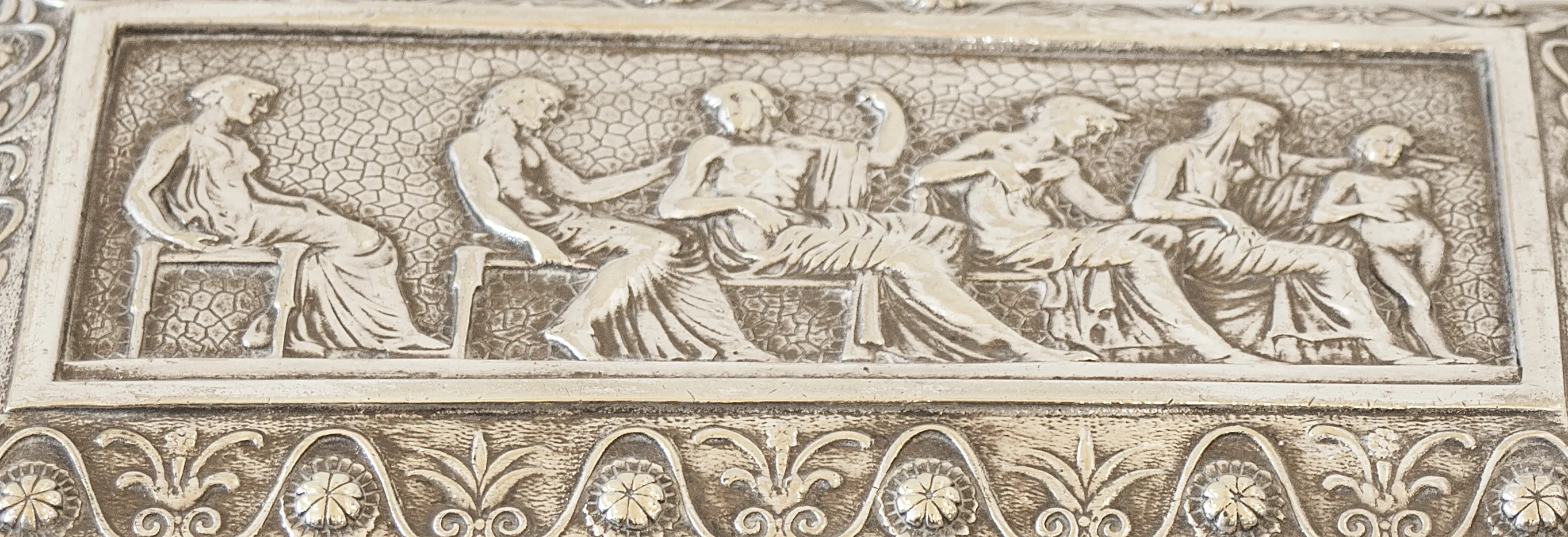 Antique box featuring relief of human figures on the lid.