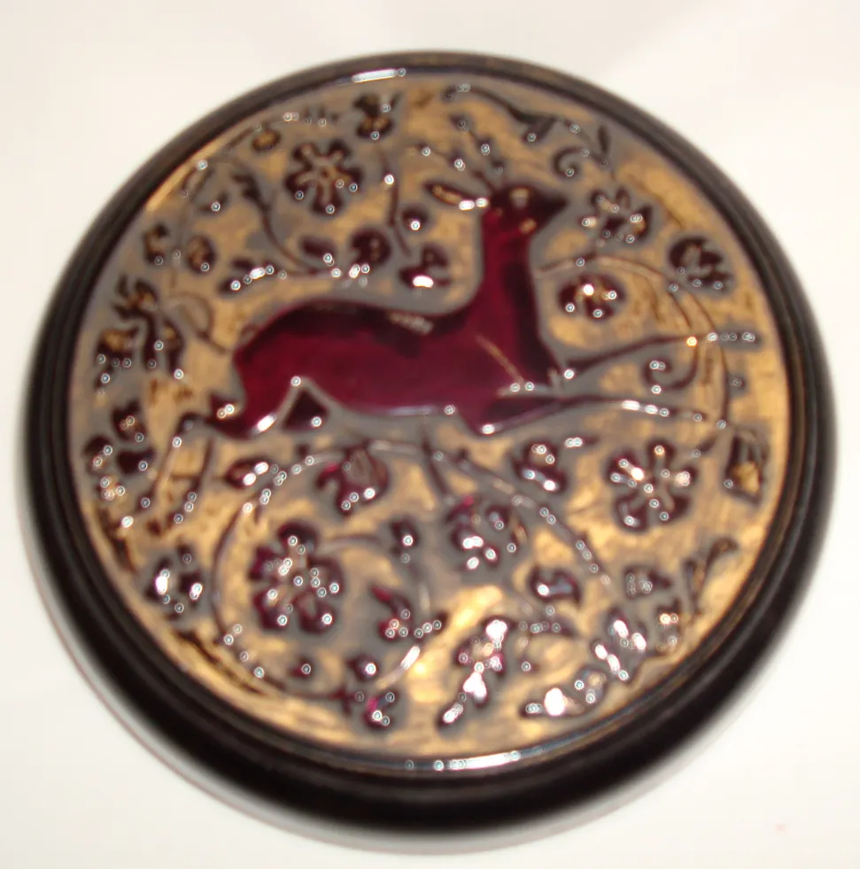 Round antique box with a relief design of a deer and flowers.