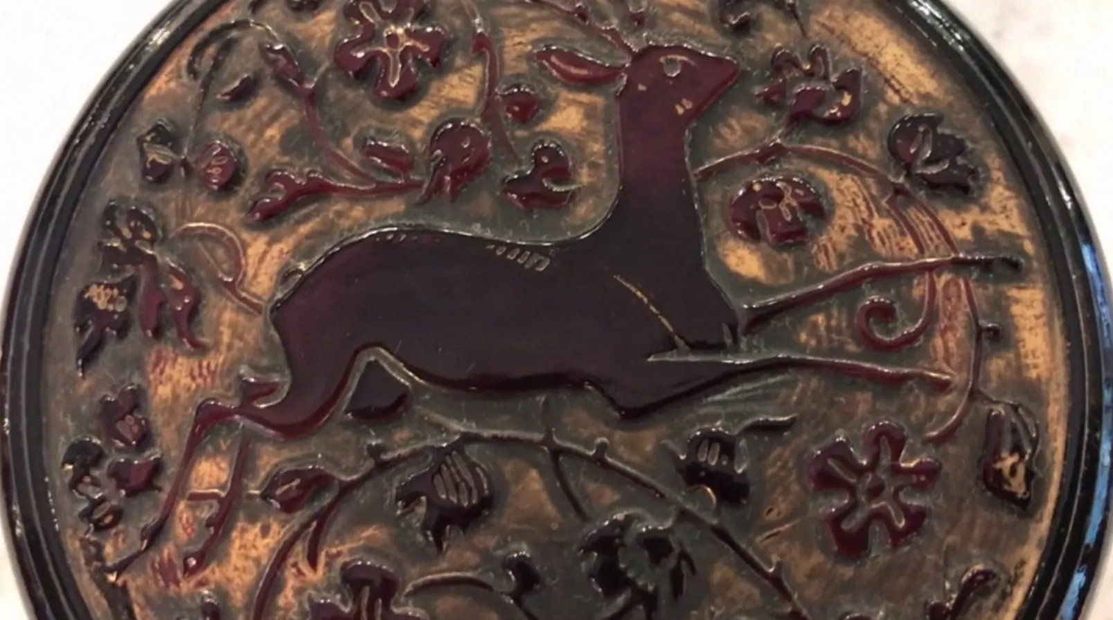 Antique box featuring a raised deer and floral patterns