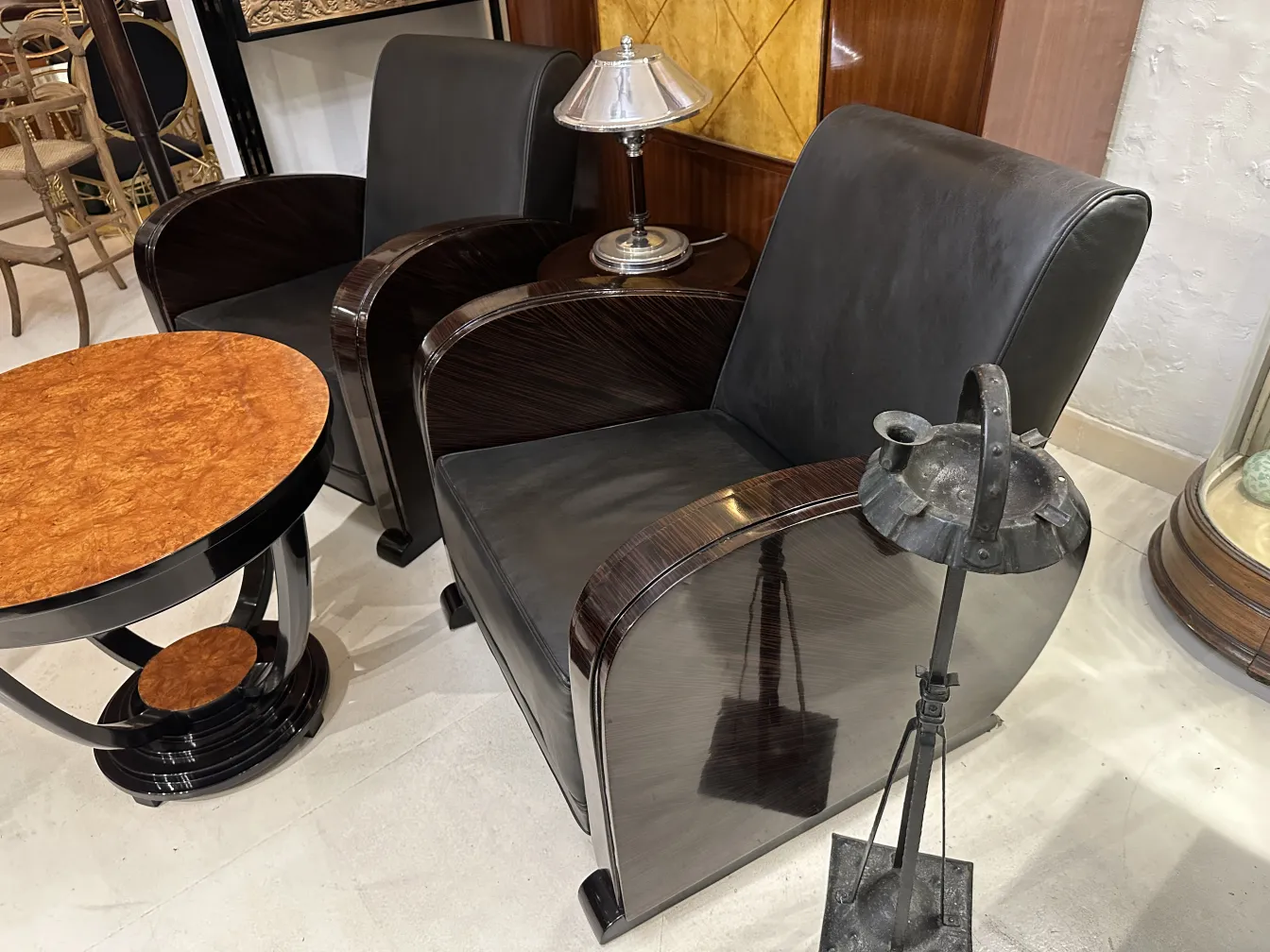 Antique standing ashtray in a decorative setting with chairs and lamp.