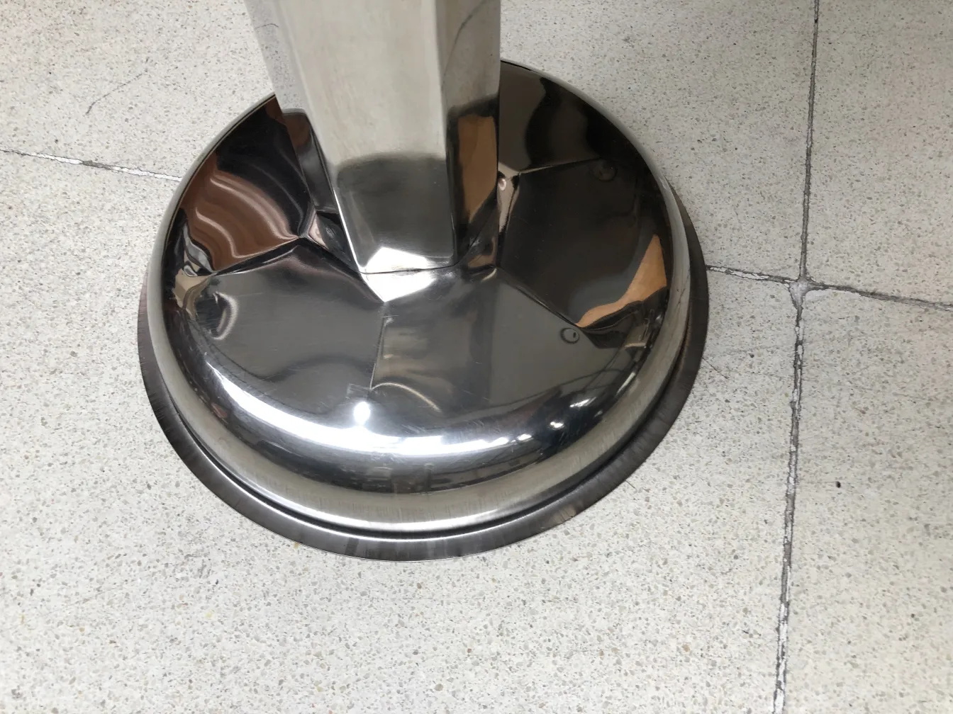 Antique standing ashtray, elegant and shiny, in a neutral setting.