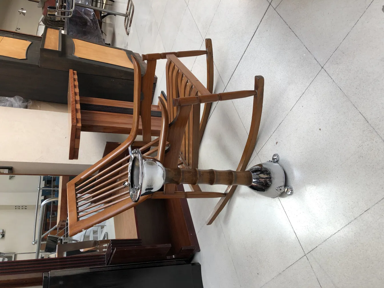 Antique standing ashtray with a classic design, surrounded by wooden furniture.