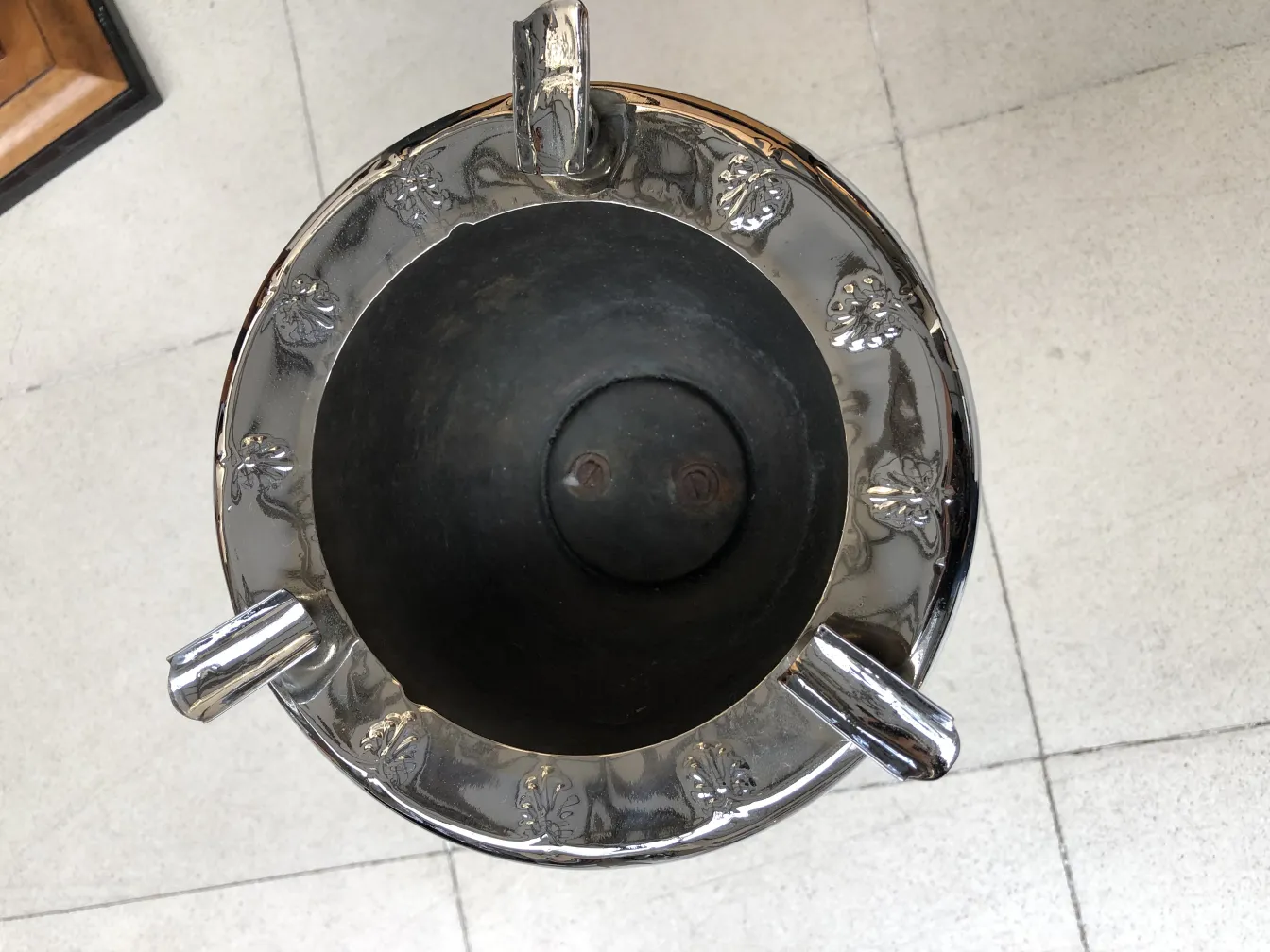 Standing ashtray featuring decorative details and an elegant design in an antique setting.