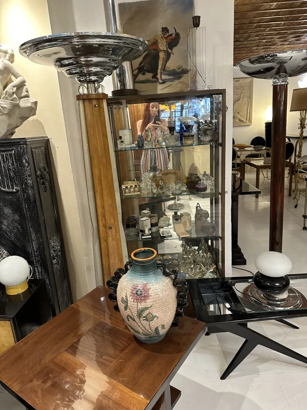 Шикарный антикорнный торшер с деревянной основой и блестящим экраном, окруженный антиквариатом.