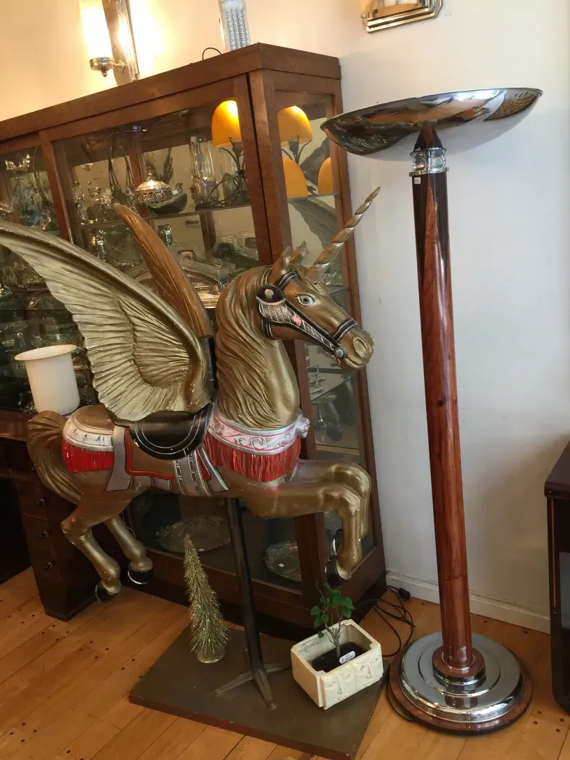 2 антикварные торшеры рядом с декоративной деревянной лошадкой.