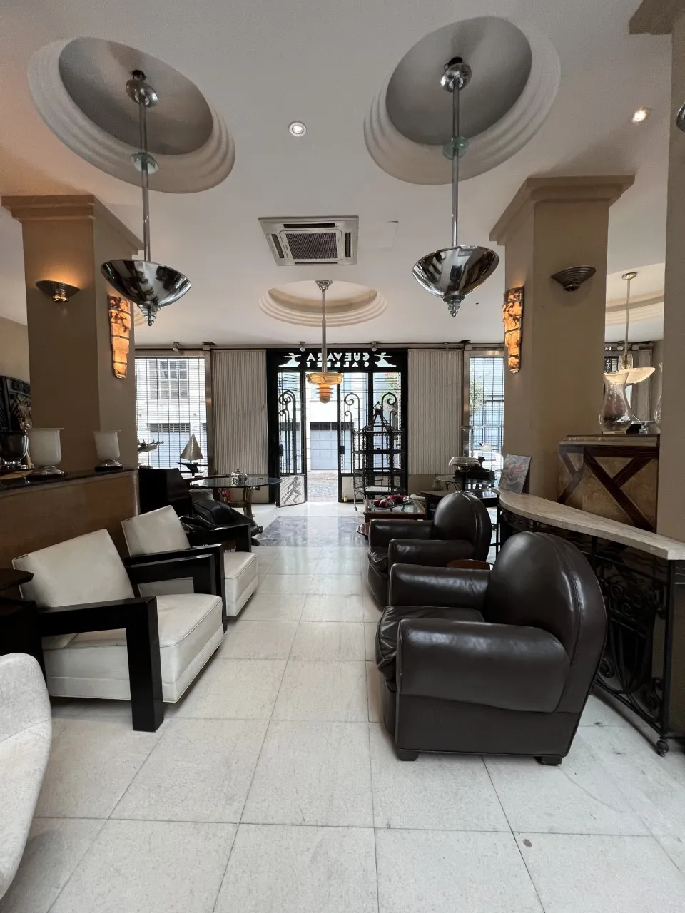 2 antique hanging lamps in an elegant setting with armchairs.