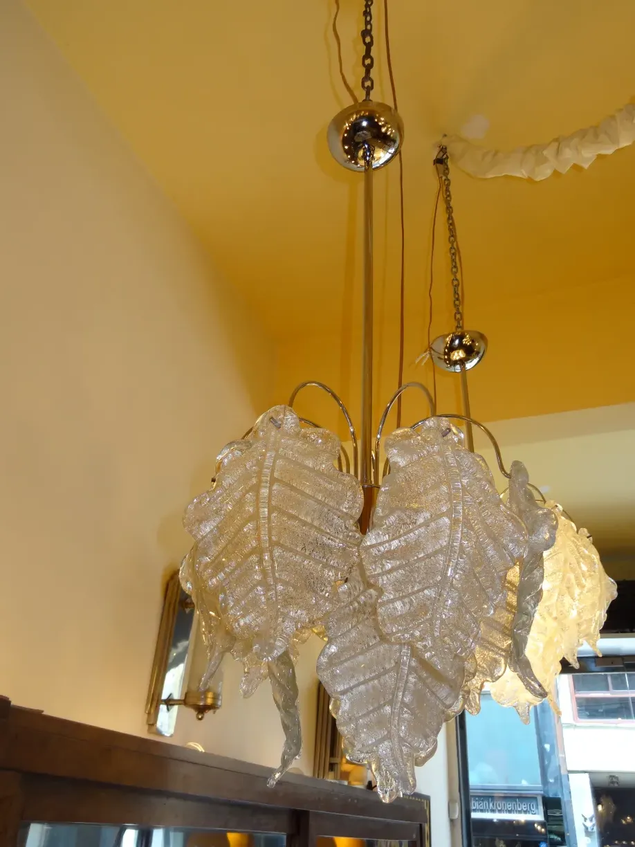 Two antique hanging lamps with shiny leaf design in a yellow room.