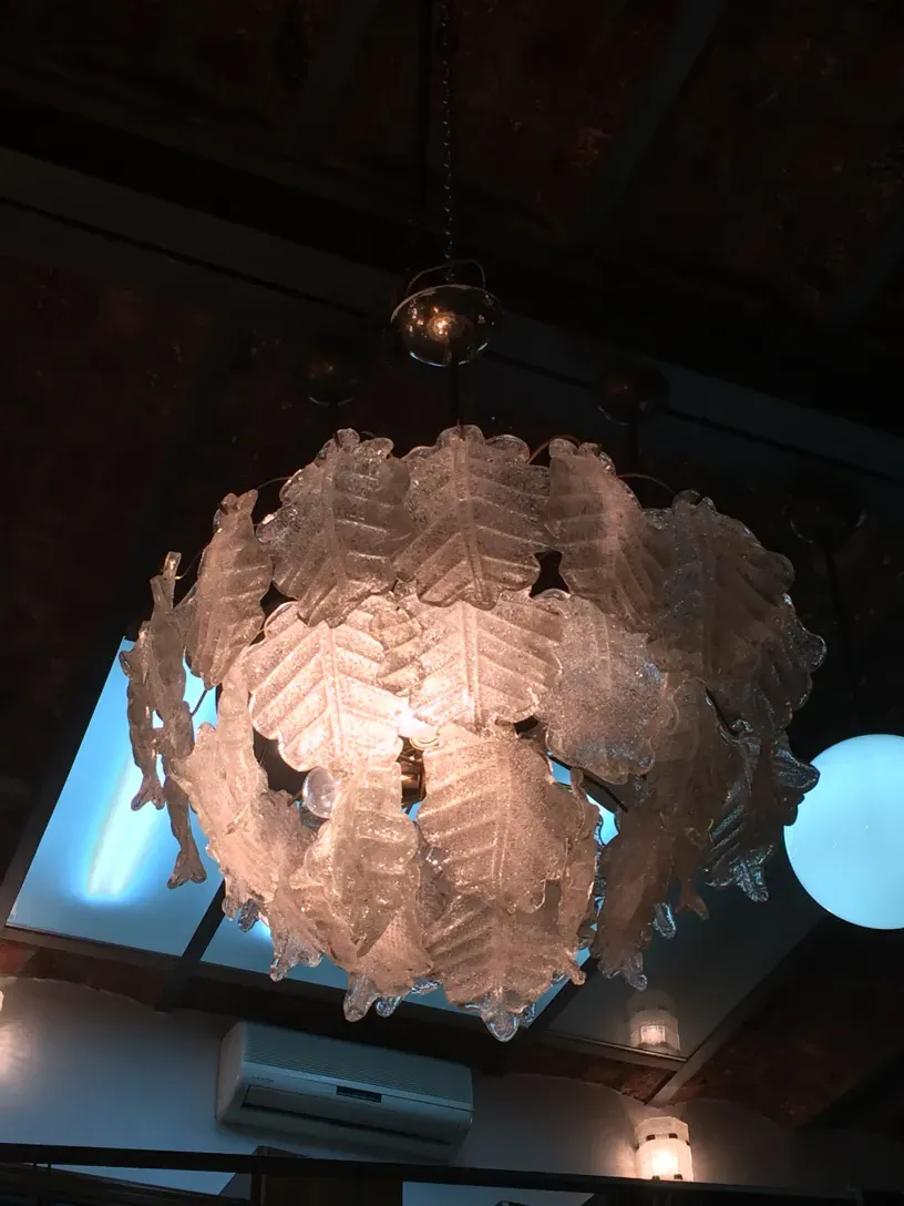 Two antique hanging lamps with decorative shapes hanging from a dark ceiling.