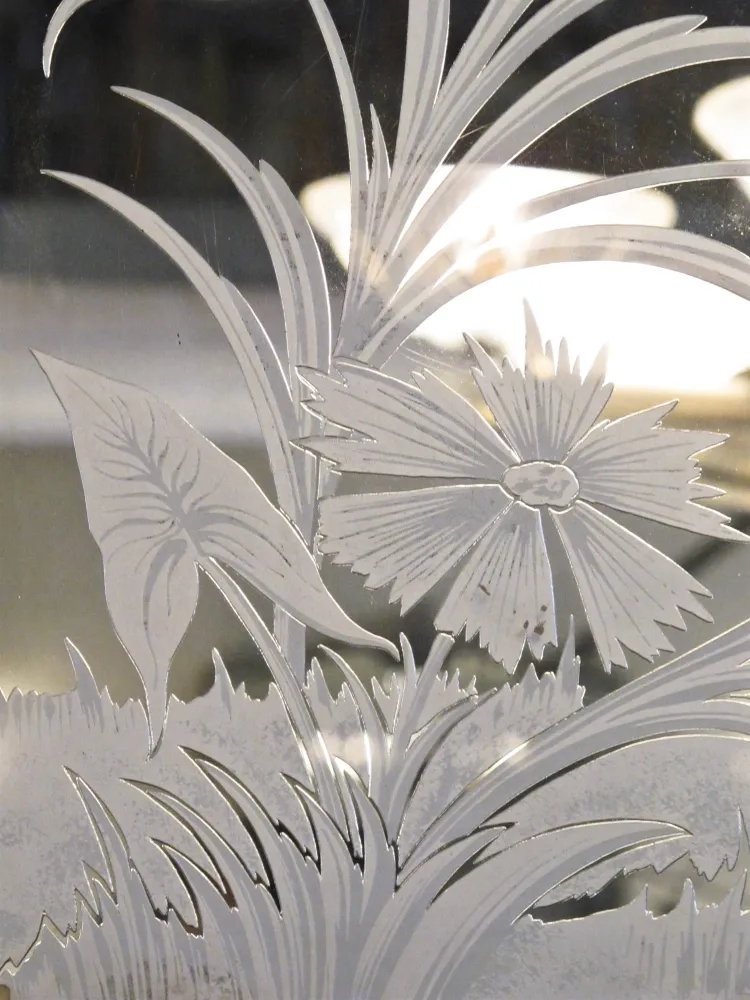 Antique mirror featuring floral and leaf engravings.