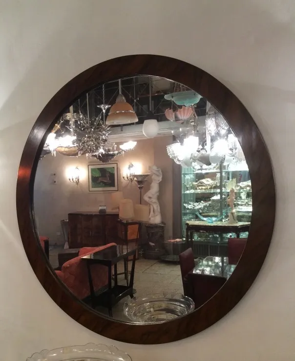 round antique mirror on wall with lights and decor