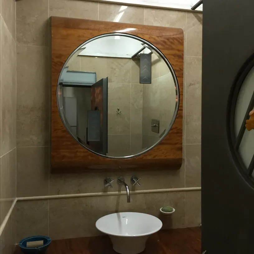 antique round mirror with wooden frame in a modern bathroom