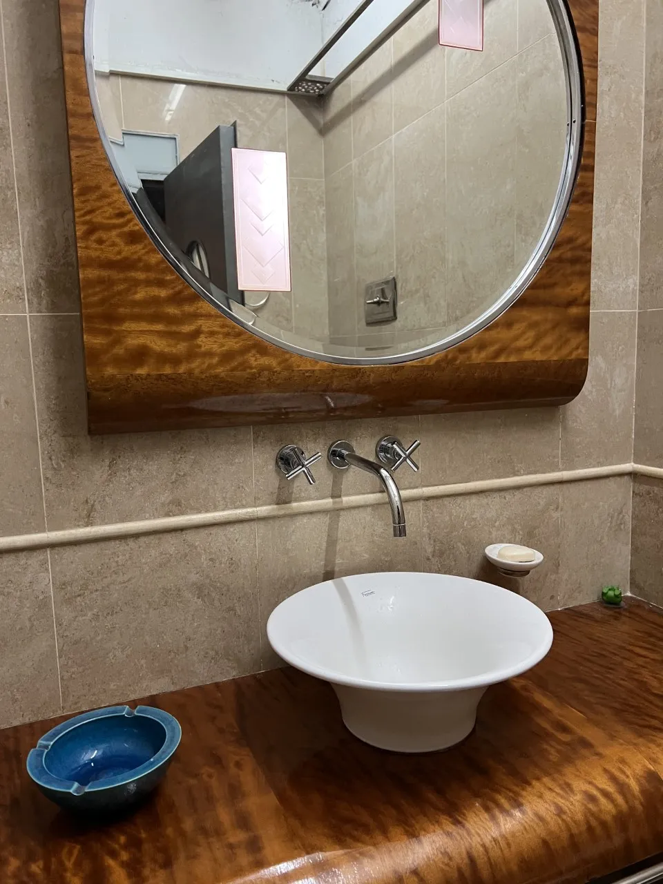 Antique round mirror above a white sink with a warm ambiance