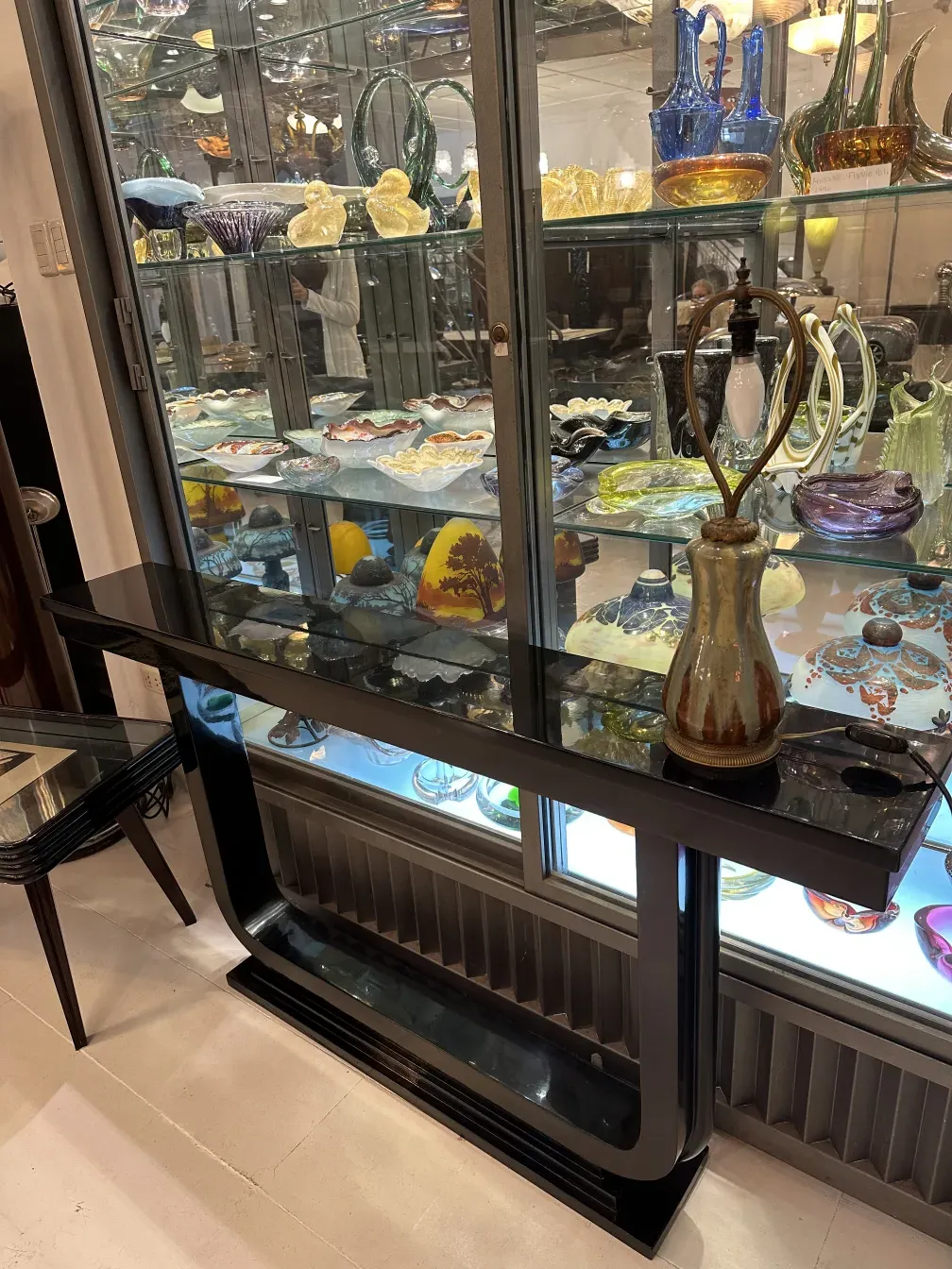 Antiga luminária de mesa decorativa com design clássico em um cenário elegante cercada por artefatos de vidro.