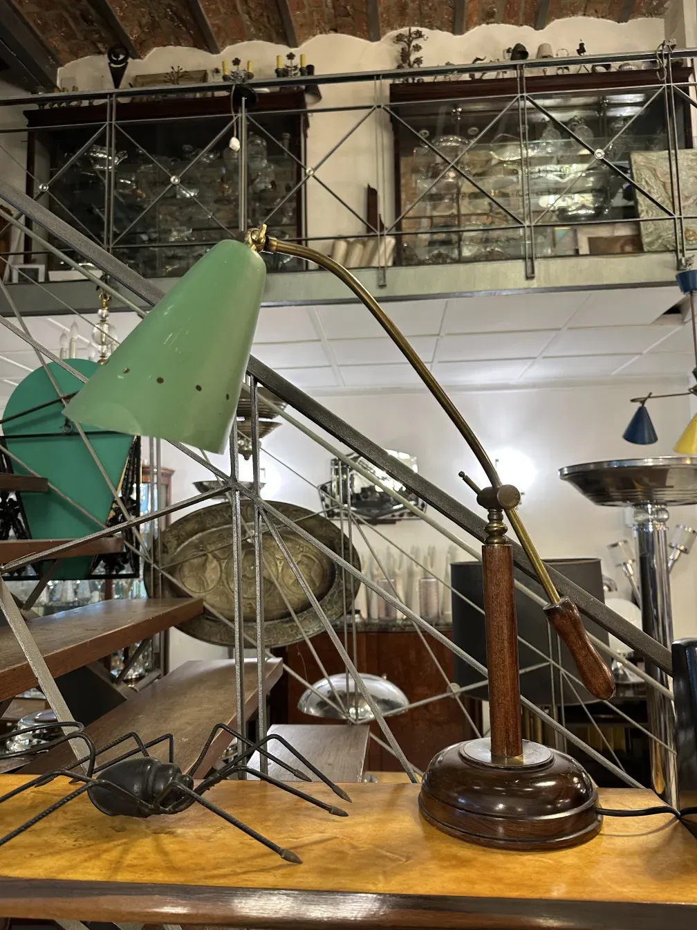 Antiga luminária de mesa verde, com base de madeira e braço ajustável, em um ambiente vintage.