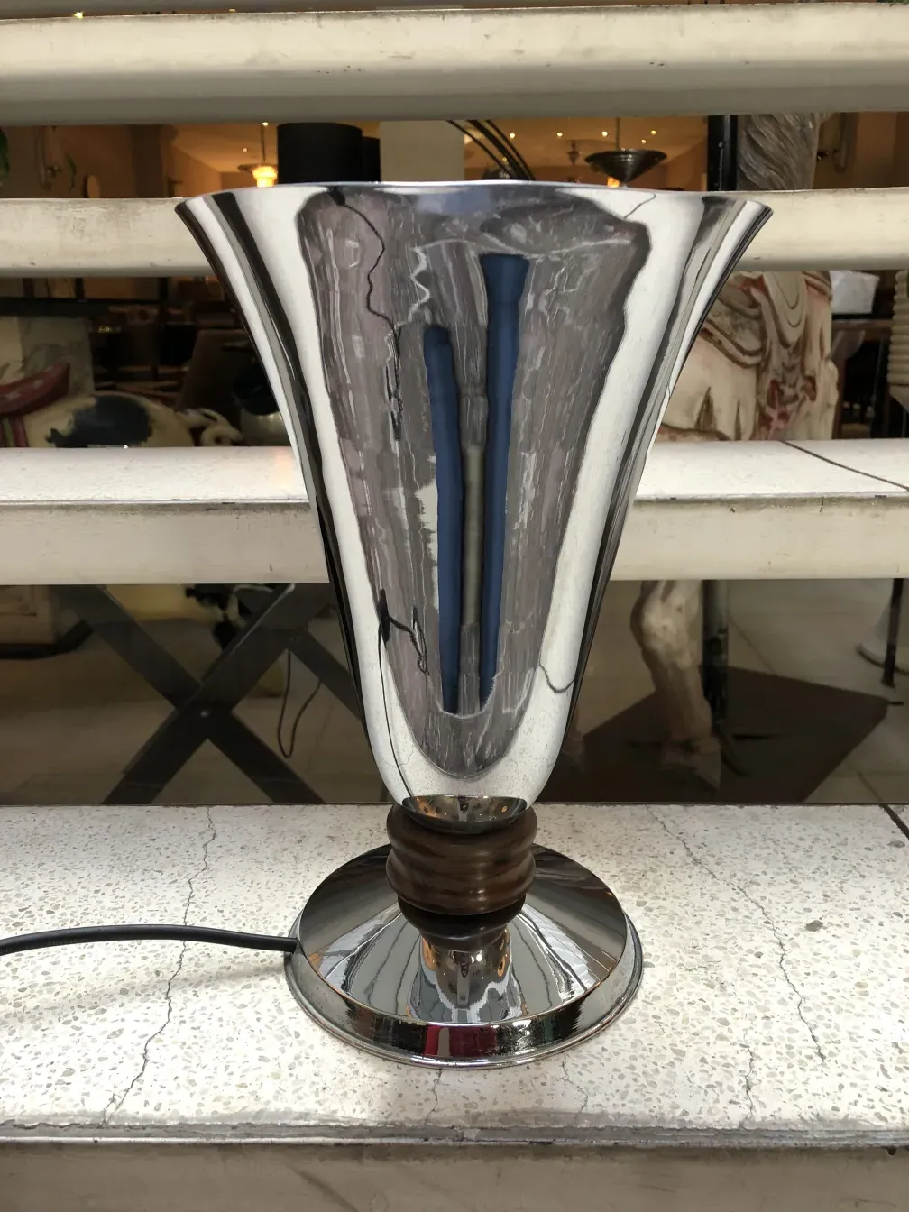 Luminária de mesa antiga com base brilhante e formato elegante em um ambiente acolhedor.