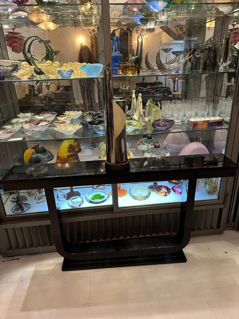 luminária de mesa antiga exposta em uma vitrine com outros objetos decorativos