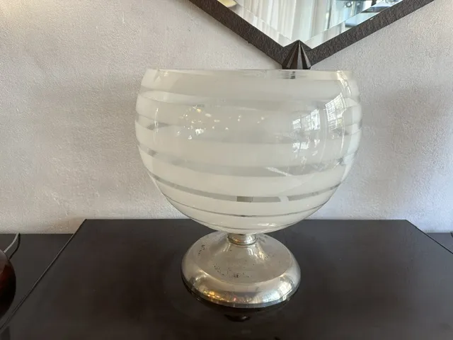 Luminária de mesa antiga com design estriado e base prateada, em um móvel escuro.