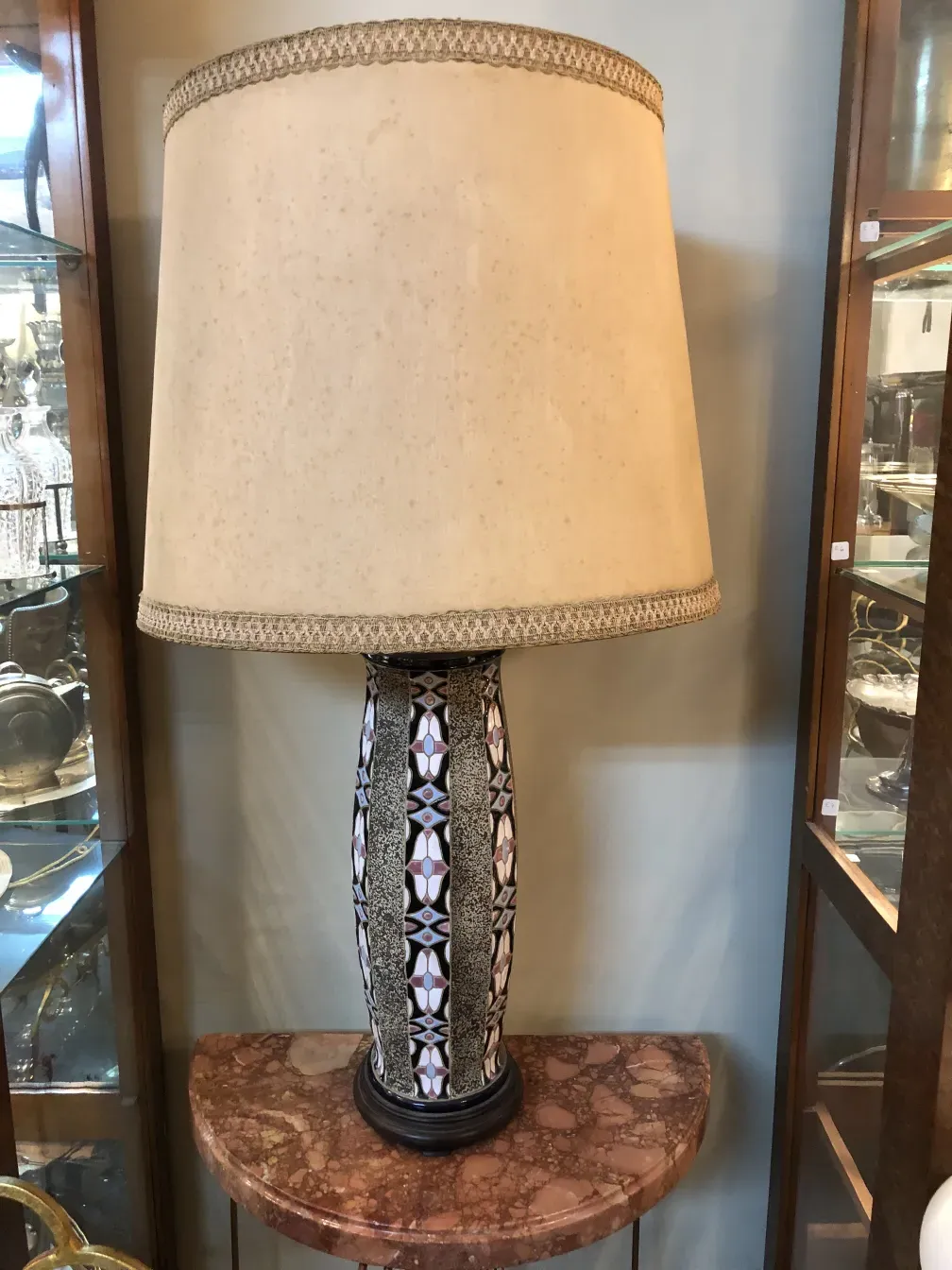 luminária de mesa antiga com cúpula bege e base decorativa escura, em um ambiente antigo