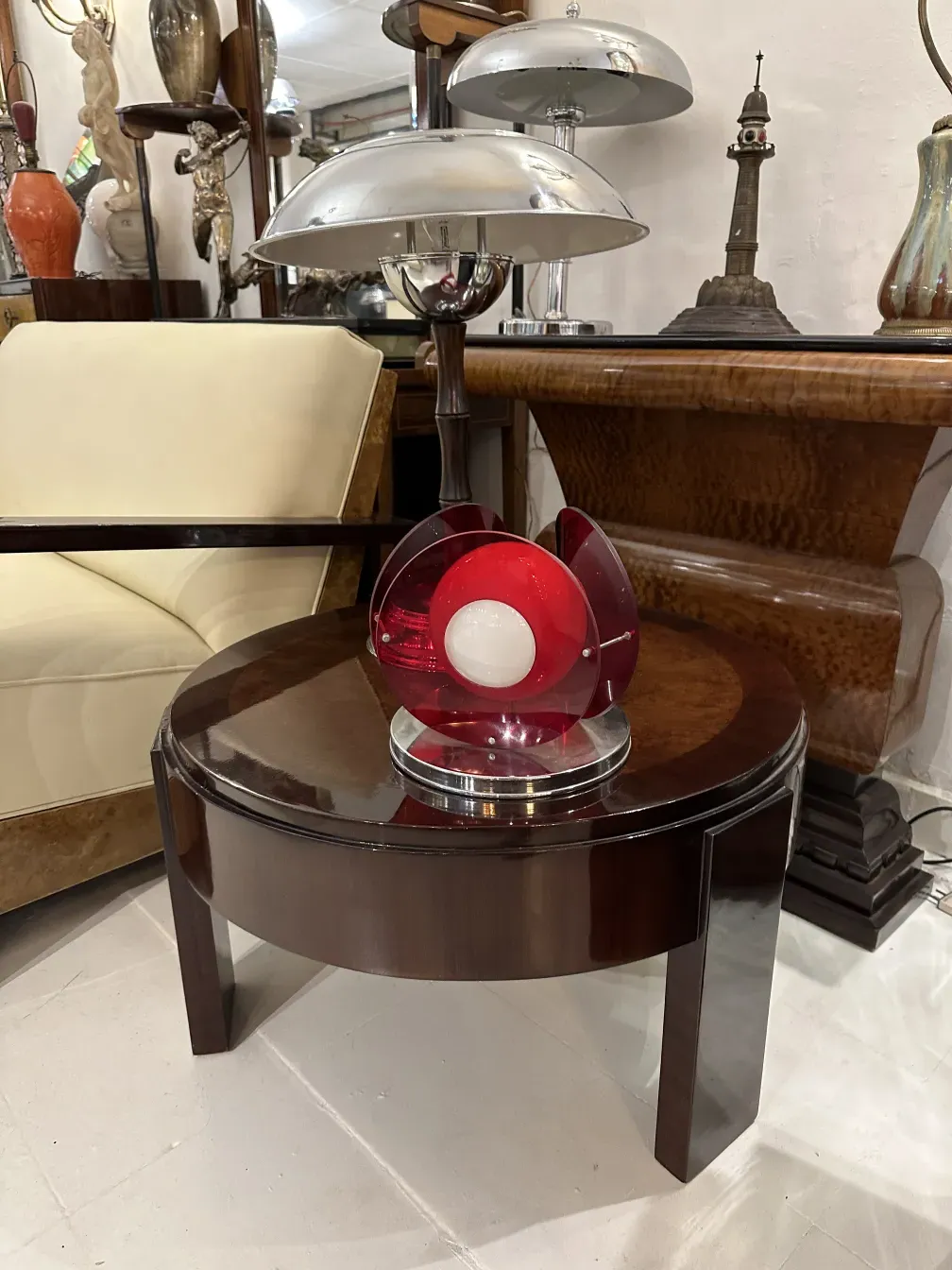 Luminária de mesa antiga com design vermelho e luz branca. A base elegante é parte de um ambiente de antiguidades.