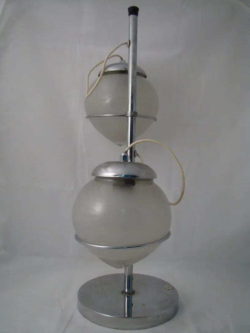 Lampada de mesa antiga com luz suave e esfera opalina em um ambiente minimalista.